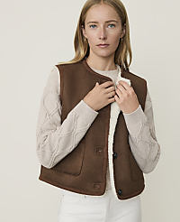 A woman in a brown shearling vest and cream sweater stands against a plain, light background. carousel Product Image 1