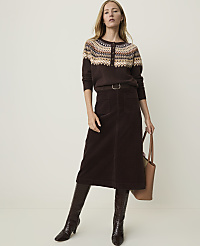 A woman in a patterned sweater, brown corduroy skirt, and croc-embossed boots stands against a plain, light-colored background, holding a tan tote bag. carousel Product Image 1