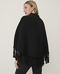 A woman in a black fringed poncho stands against a plain, light-colored background. carousel Product Image 2