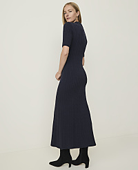 A woman in a navy cable-knit dress and black boots stands against a plain, light-colored background. carousel Product Image 2