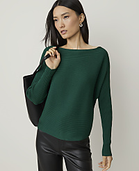 A woman in a green sweater and black pants stands against a plain background, carrying a black tote bag. carousel Product Image 1
