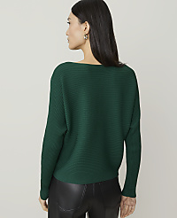 A woman in a green ribbed sweater and black leather pants stands against a plain, light gray background. carousel Product Image 2