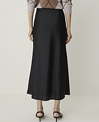 A person stands in a plain studio, wearing a black midi skirt and a patterned sweater, with their back to the camera. carousel Product Image 3