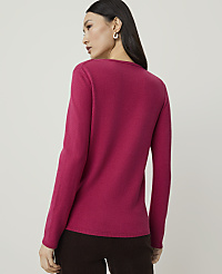 A woman in a pink sweater stands against a plain, light brown background. carousel Product Image 2