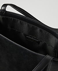 A black leather tote bag with a branded label is shown against a plain white background. carousel Product Image 2