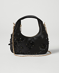 A black satin handbag adorned with black sequins and beads sits on a light gray background, with a delicate gold chain strap draped across it. carousel Product Image 1