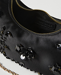 A black satin handbag adorned with sequins and beads is shown in the foreground, with a glimpse of its interior and a gold chain strap, against a plain white background. carousel Product Image 2