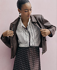 A woman in a patterned blouse and skirt, wearing a brown leather jacket, stands against a soft pink background. carousel Product Image 3