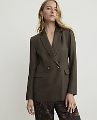 A woman in a dark brown double-breasted blazer and patterned pants stands against a plain white background. carousel Product Image 1