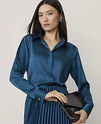 A woman in a teal satin blouse and pleated skirt holds a black clutch against a plain background. carousel Product Image 1