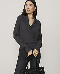 A woman in a dark grey wrap sweater and black jeans holds a black textured tote bag in front of a plain grey background. carousel Product Image 1