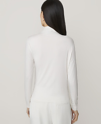 A woman in a white turtleneck and pants stands against a plain white background. carousel Product Image 2