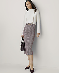 A woman in a white blouse and plaid skirt stands against a plain white background, holding a dark handbag. carousel Product Image 1