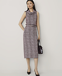 A woman in a plaid sleeveless turtleneck and skirt stands against a plain background, holding a dark handbag. carousel Product Image 4