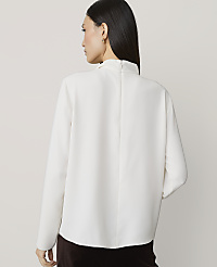 A woman in a white blouse stands against a plain, light background. carousel Product Image 2
