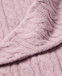 A close-up of a soft, pink cable-knit sweater fills the frame, with the textured fabric creating a cozy and inviting foreground against a subtly blurred background. carousel Product Image 2