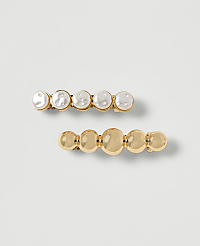 Two gold barrettes, one adorned with pearls and the other with smooth gold spheres, rest on a plain white background. carousel Product Image 1