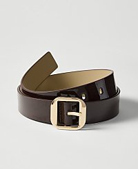 A glossy brown belt with a gold buckle lies on a white surface, with a soft shadow cast behind it. carousel Product Image 1