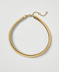 A gold herringbone necklace lies on a plain white background. carousel Product Image 1