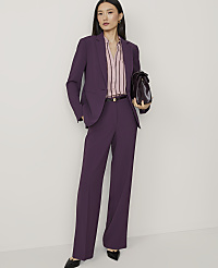 A woman in a purple pantsuit stands against a plain white background, holding a dark brown briefcase. carousel Product Image 1