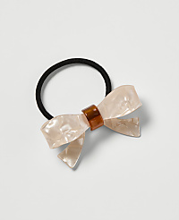 A pearlescent bow hair tie with a tortoiseshell accent rests on a plain white background. carousel Product Image 1