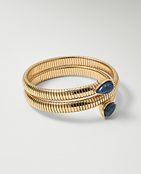 A coiled gold snake bracelet with two blue teardrop gems rests on a plain white background. carousel Product Image 1