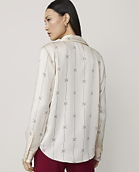 A woman in a cream-colored patterned blouse and maroon pants stands against a plain, light background. carousel Product Image 2