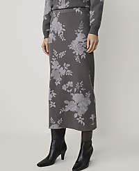 A person stands wearing a floral-patterned skirt and sweater, with black boots, against a plain white background. carousel Product Image 2