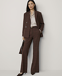 A woman in a brown plaid suit stands against a plain, light-colored background, holding a dark handbag. carousel Product Image 1