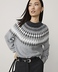 A woman in a grey fair isle sweater and black belt stands against a plain, light grey background. carousel Product Image 1