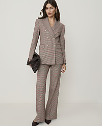 A person in a white top and plaid flared pants stands against a plain background.