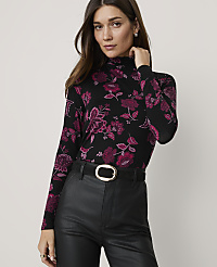 A woman in a black floral turtleneck and black leather pants stands against a plain white background. carousel Product Image 1