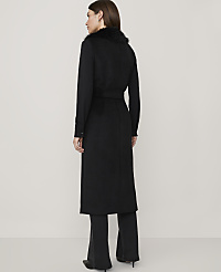A woman in a long black coat with a fur collar stands against a plain, light gray background. carousel Product Image 2