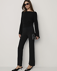 A woman in a black sweater and pants, holding a clutch, stands against a plain white background. carousel Product Image 1