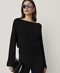 A woman in a black off-the-shoulder sweater and sunglasses holds a black clutch in front of a plain background. carousel Product Image 1