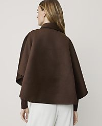 A woman from behind wears a brown cape over a maroon sweater and white pants against a plain background. carousel Product Image 2