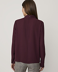 A woman in a burgundy mock-neck blouse and plaid pants stands against a plain gray background. carousel Product Image 2