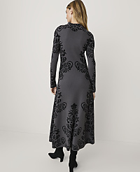 A woman in a long-sleeved gray dress with black ornate patterns stands against a plain white background. carousel Product Image 2
