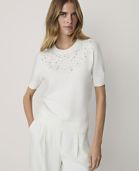 A woman in a white pearl-embellished sweater and white pants stands against a plain white background. carousel Product Image 1