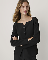 A woman in a black jacket with a square neckline stands with her arms crossed against a plain gray background. carousel Product Image 1