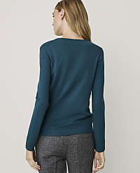 A woman in a teal sweater and patterned pants stands against a plain, light-colored background. carousel Product Image 2