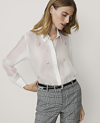 A woman in a sheer white blouse with jeweled embellishments and plaid pants stands against a plain white background. carousel Product Image 1