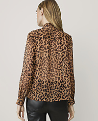 A woman in a leopard print blouse stands against a plain, light-colored background. carousel Product Image 2