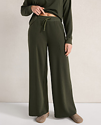 A person in olive green wide-leg pants and slippers stands against a neutral, textured background. carousel Product Image 3