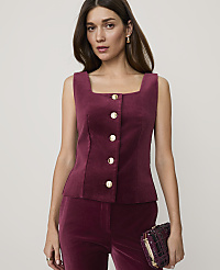 A woman in a burgundy corduroy vest and pants holds a patterned clutch in front of a plain background. carousel Product Image 1