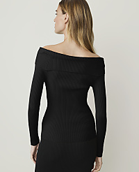 A woman in a black off-the-shoulder dress holds a jeweled clutch in the foreground against a plain, light background. carousel Product Image 2