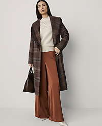 A woman in a plaid coat and wide-leg pants stands against a plain, light-colored background, holding a dark handbag. carousel Product Image 4
