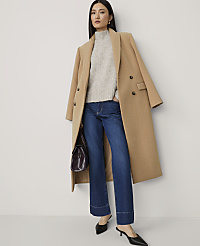 A woman in a camel coat, grey sweater, and wide-leg jeans stands against a plain white background. carousel Product Image 1
