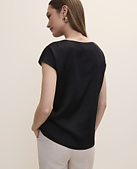 A woman in a black top and beige pants stands against a plain, light-colored background. carousel Product Image 2
