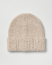 A light beige cable-knit beanie sits centered against a plain, light gray background. carousel Product Image 1
